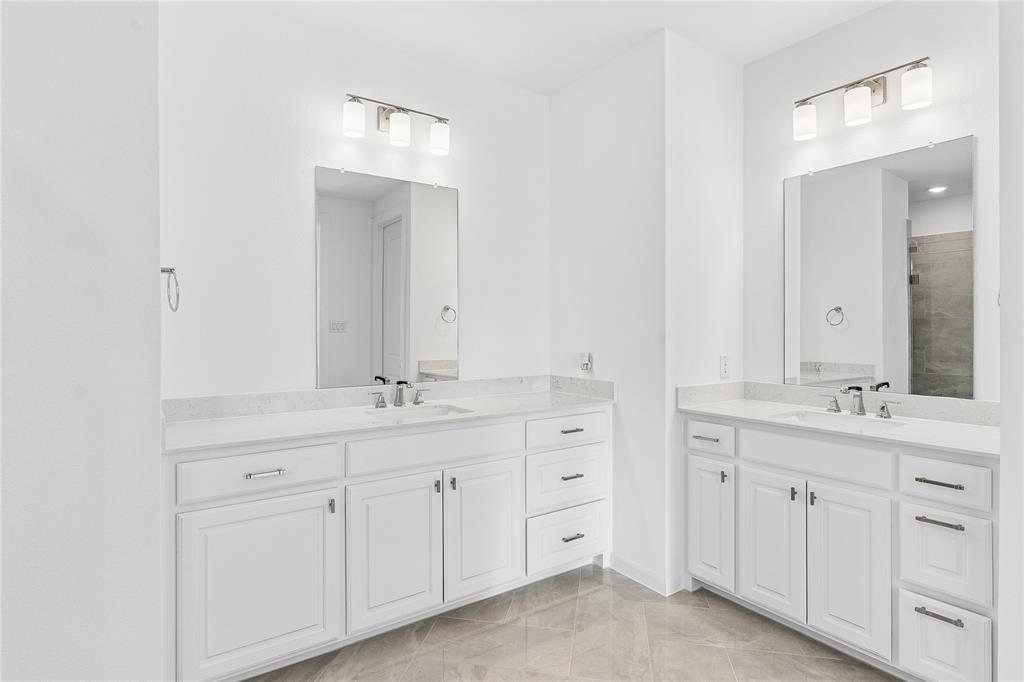 Dual vanity sinks with white cabinetry and stone countertops
