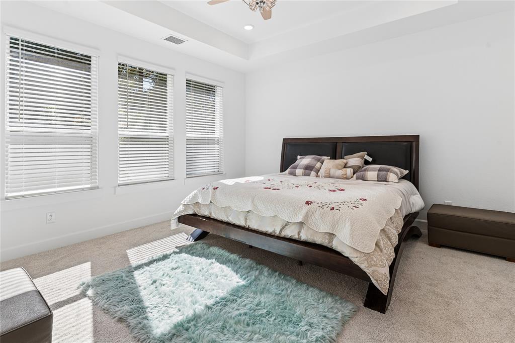 Tray ceiling with recessed lighting, ceiling fan, three windows with blinds, and carpeted flooring