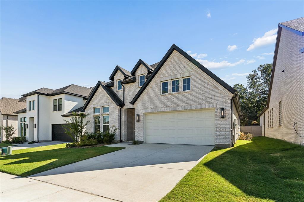 White brick exterior with black trim, a gabled roofline, an attached two-car garage, and a concrete driveway