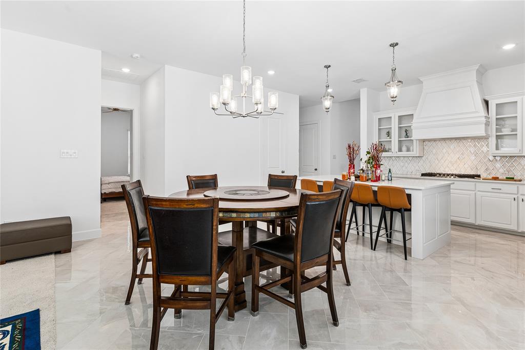 Open-concept kitchen and dining area with light-toned tile flooring, recessed lighting, and a chandelier
