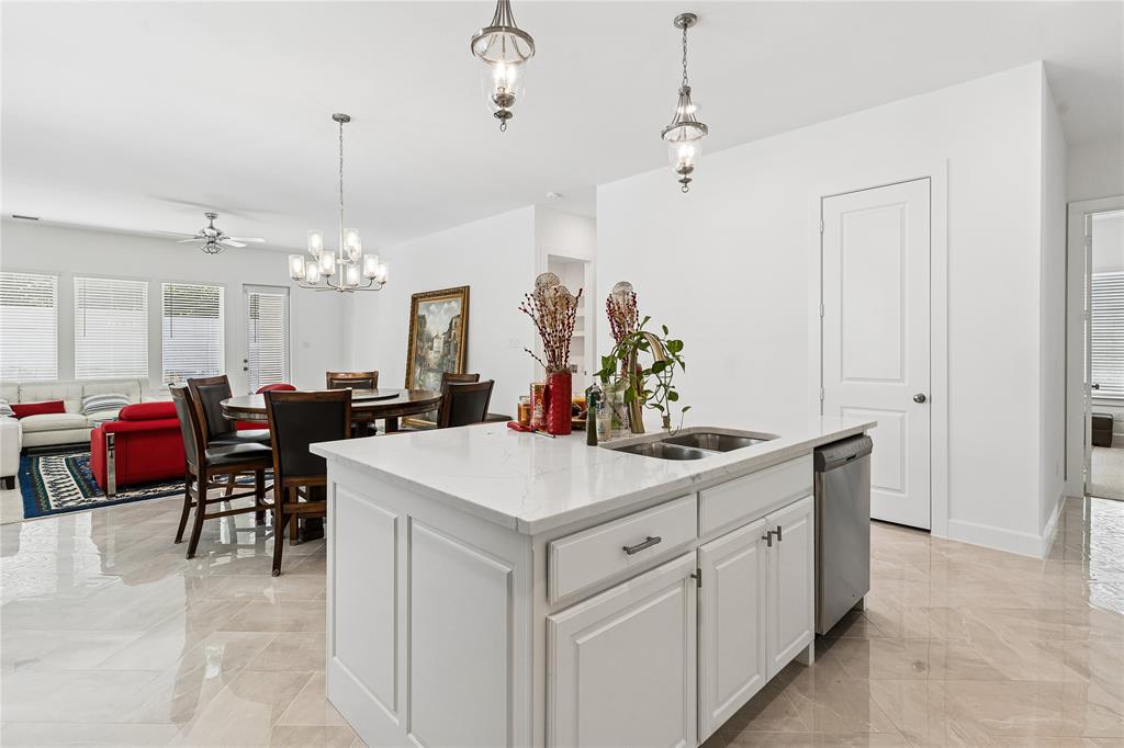 Kitchen island with built-in stainless steel sink, white cabinetry, and light-colored countertop