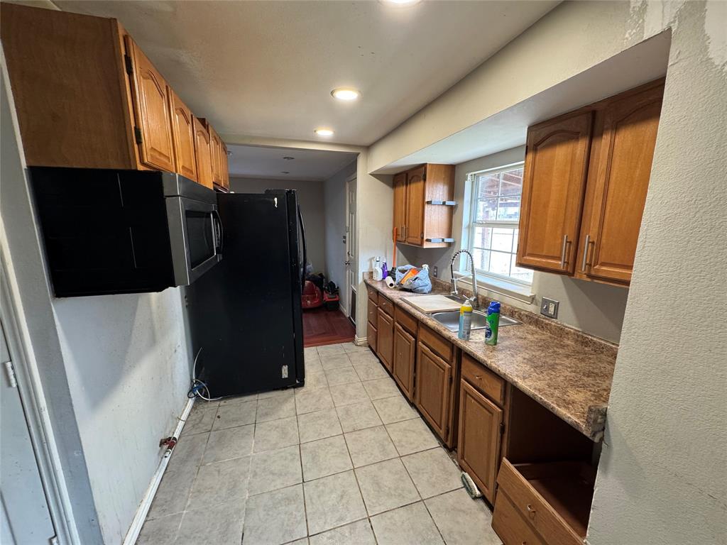 Kitchen featuring wood cabinetry, tiled flooring, built-in microwave, and a stainless steel sink with a single-handle faucet
