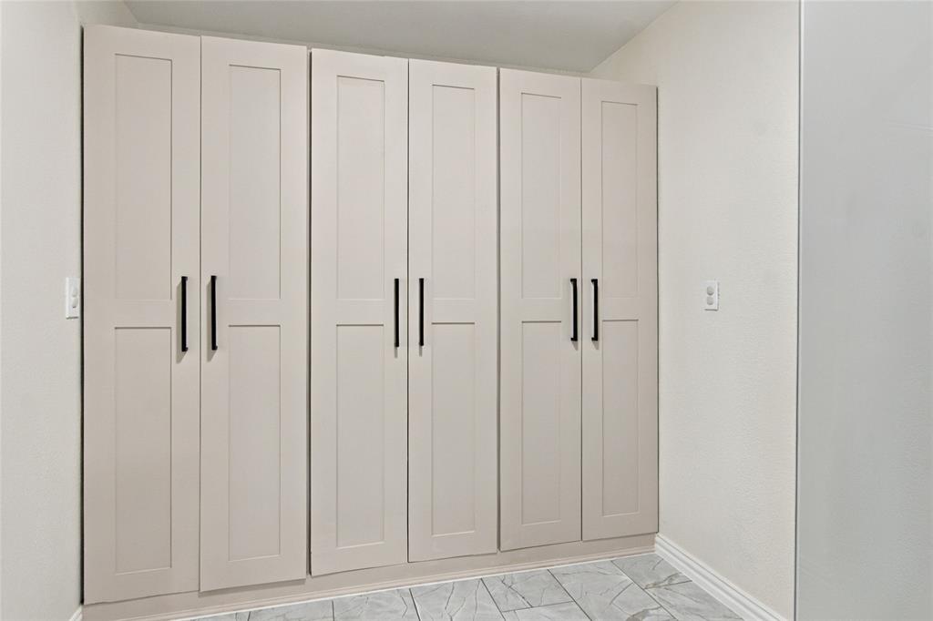 Built-in cabinetry with flat panel doors and matte black hardware, set against light-toned walls and patterned flooring
