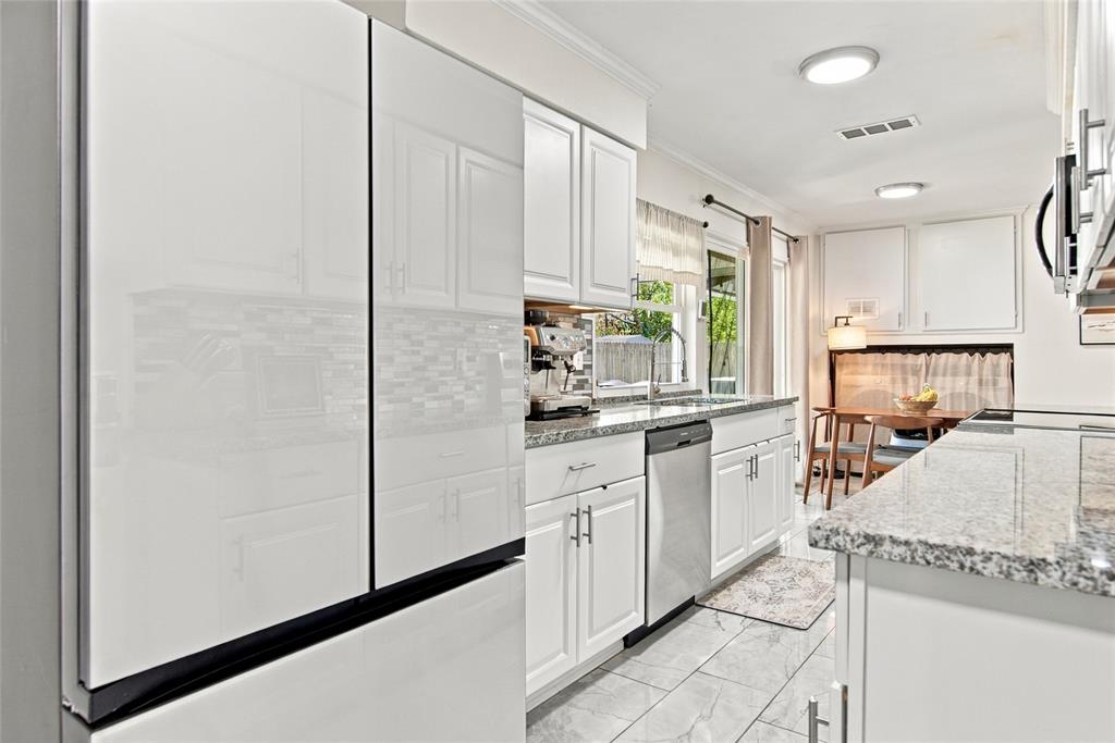 White cabinetry with brushed nickel hardware, light-toned granite-style countertops, mosaic tile backsplash, and recessed lighting