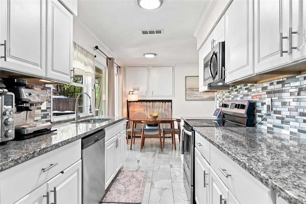 White cabinetry with brushed nickel hardware, granite countertops, stainless steel appliances, mosaic tile backsplash, and tile flooring