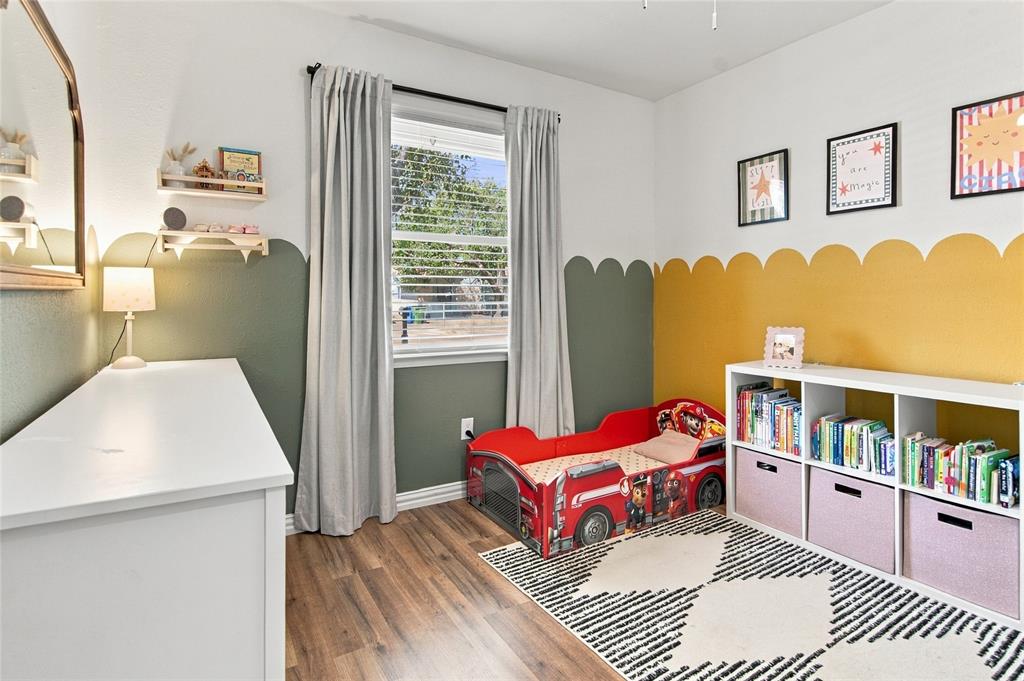Wood-finish flooring, built-in shelving unit, natural light from a window, and decorative wall treatments