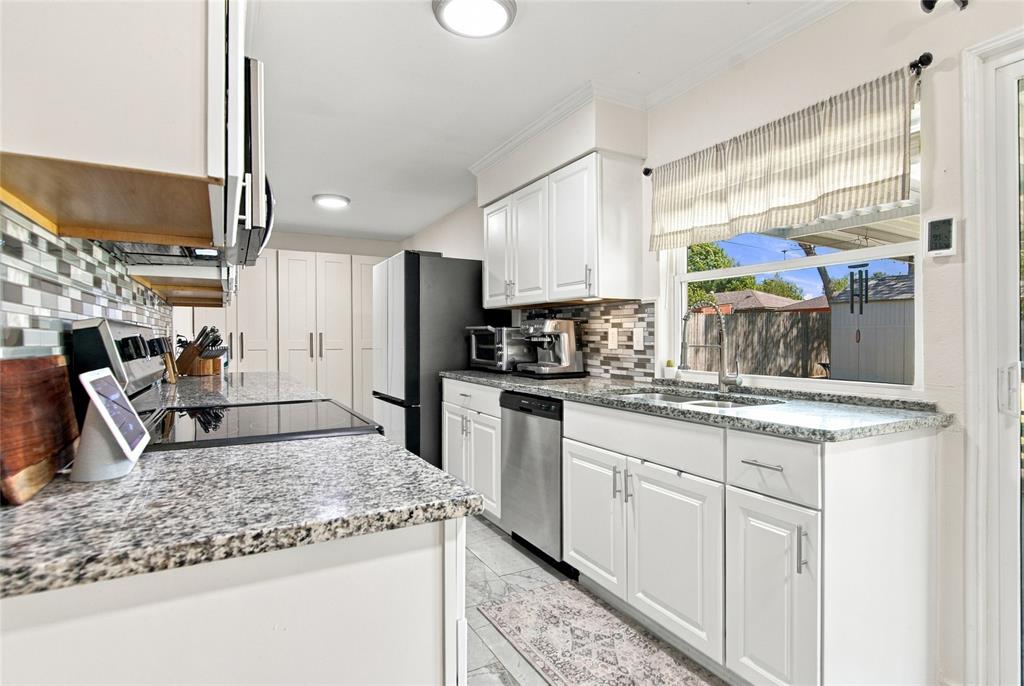White cabinetry, speckled countertops, tile backsplash, stainless steel dishwasher, and a sliding glass door
