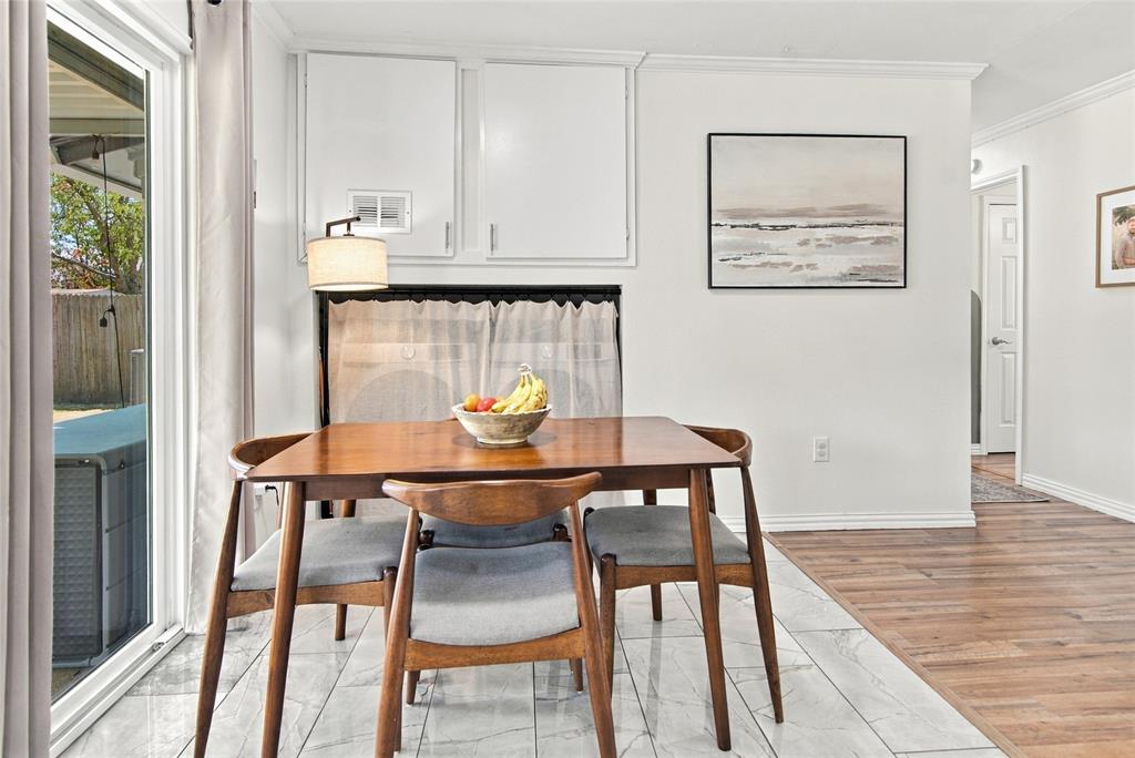 Sliding glass door, white wall cabinetry, crown molding, wood-finish flooring, and light-toned tile flooring