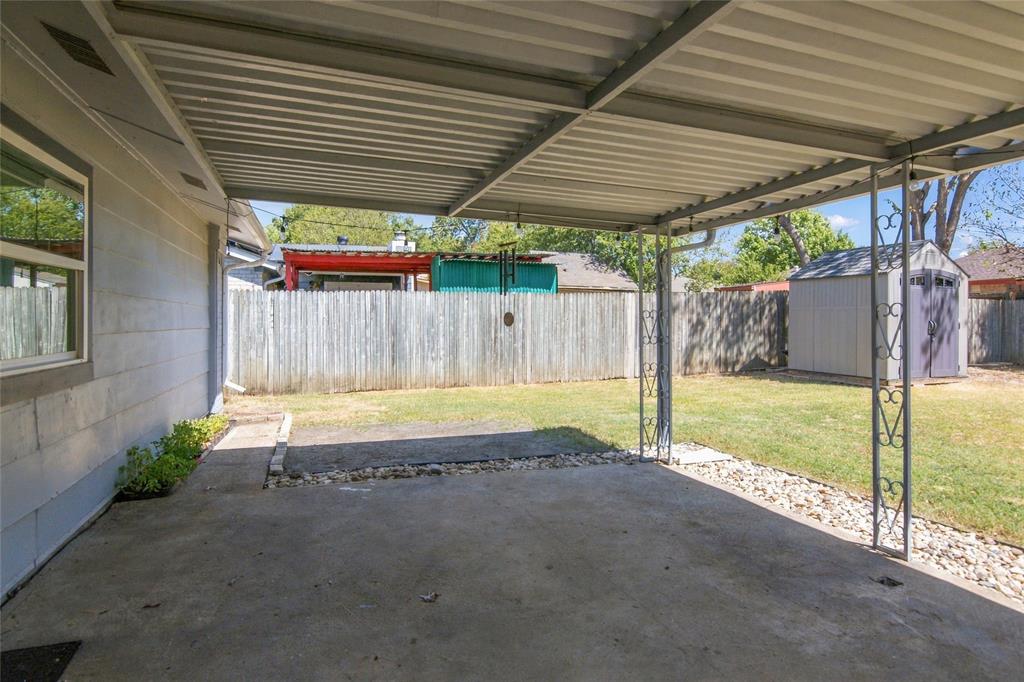 Covered patio with a concrete surface, metal support columns, and adjacent crushed stone landscaping