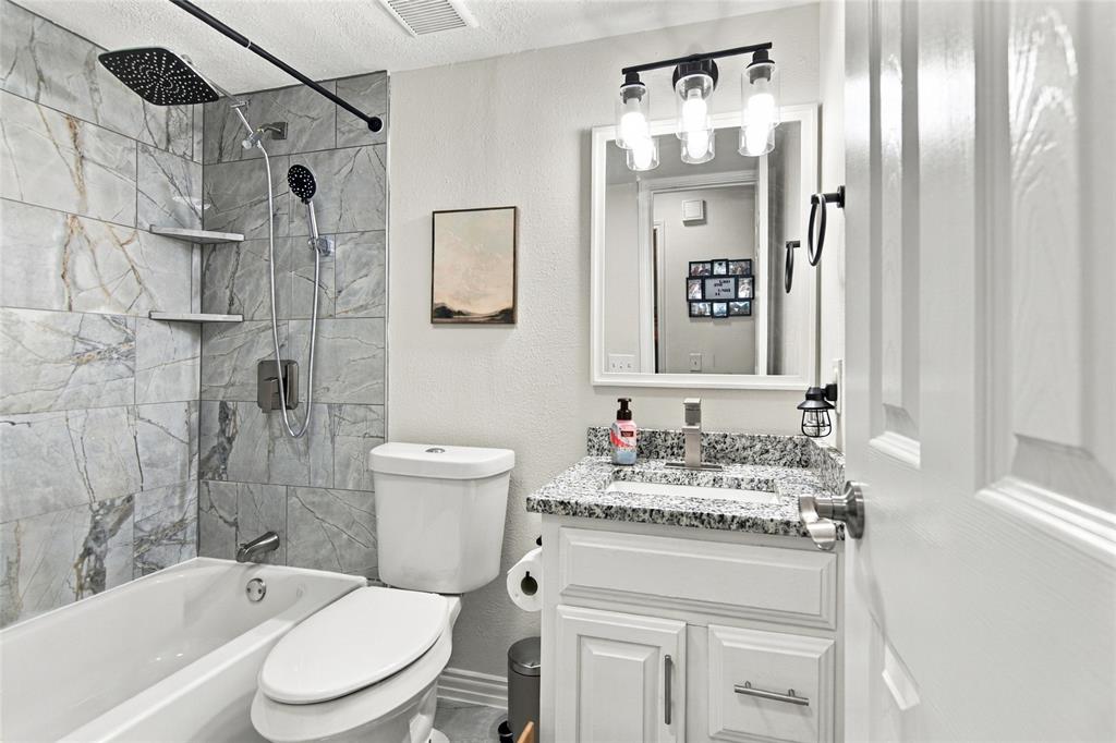 Shower/tub combination with gray stone-look tile surround and built-in shelving