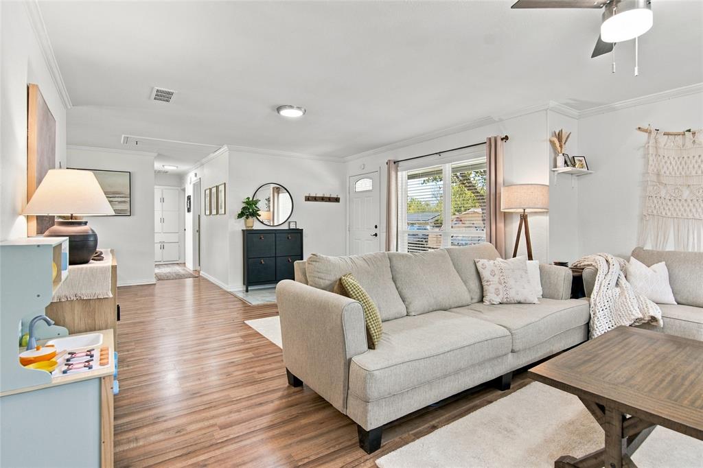 Wood-finish flooring, white walls, crown molding, and a ceiling fan with integrated lighting