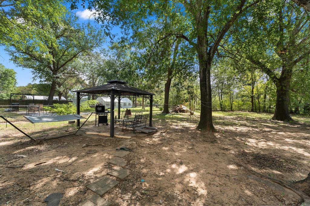 LARGE LOT with mature shade trees, a metal-framed gazebo, and a stone paver pathway