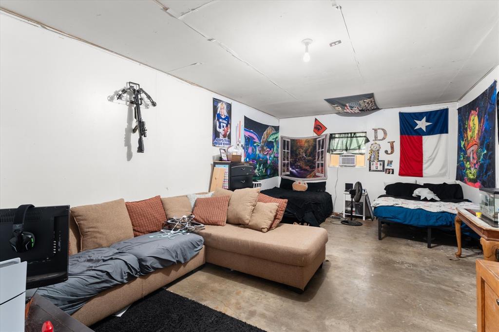 Interior room featuring exposed concrete flooring, white walls, and a single ceiling-mounted light fixture