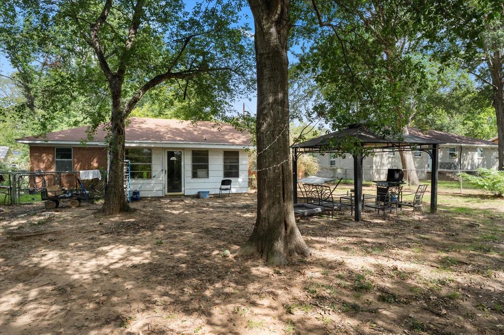 Spacious backyard featuring mature trees and a metal-frame gazebo structure