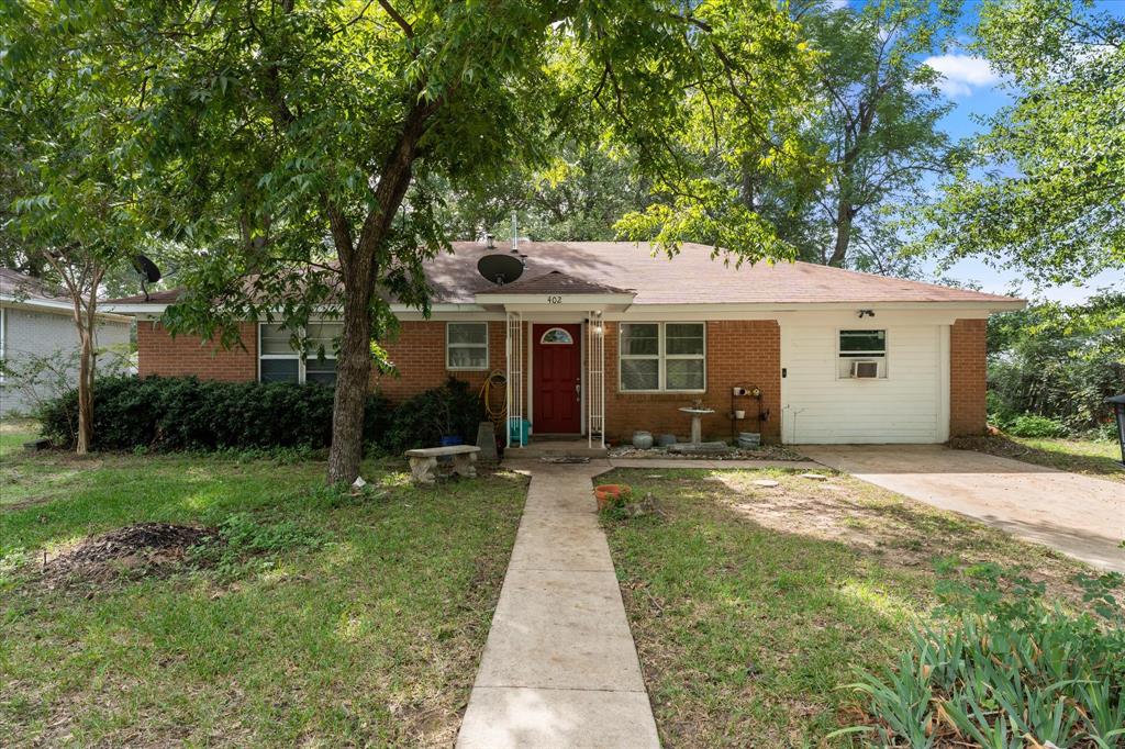 Single-story brick exterior featuring a concrete walkway with mature pecan trees