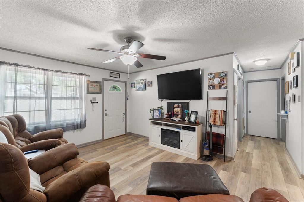 Wood-finish flooring, ceiling fan with integrated lighting, multi-panel front door with glass insert, and neutral wall tones