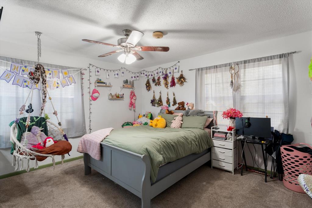 Room featuring neutral wall-to-wall carpeting, dual windows with soft-filter window treatments, and a central ceiling fan with integrated lighting