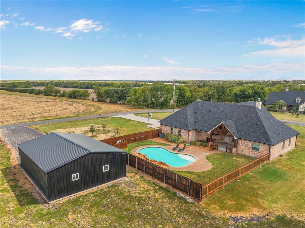 Brick exterior residence featuring a gabled roof, an inground swimming pool, and an outdoor patio space