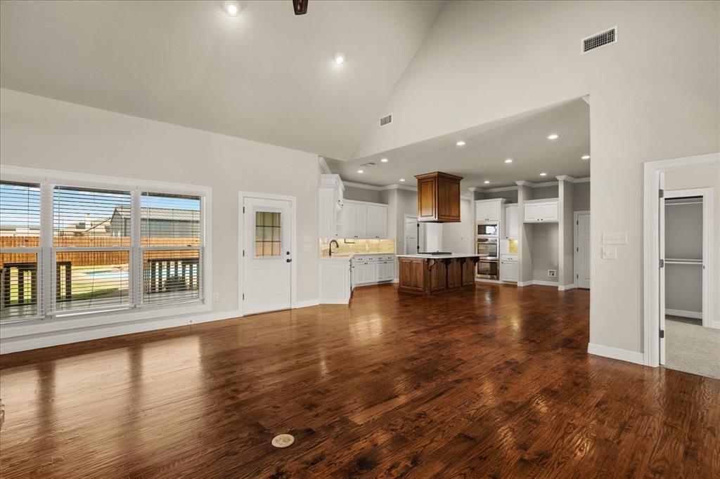 Vaulted ceiling, recessed lighting, wood-finish flooring, white cabinetry, and a kitchen island with a wood base