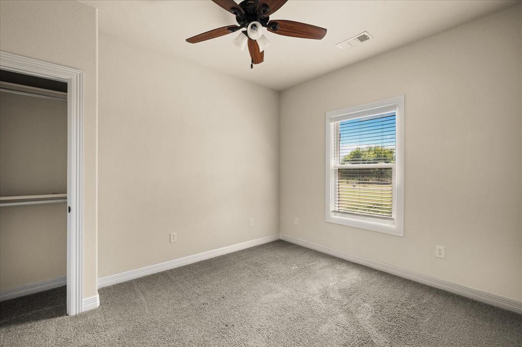 Recessed closet with a built-in shelf and hanging rod, carpeted flooring, and a ceiling fan with light fixture