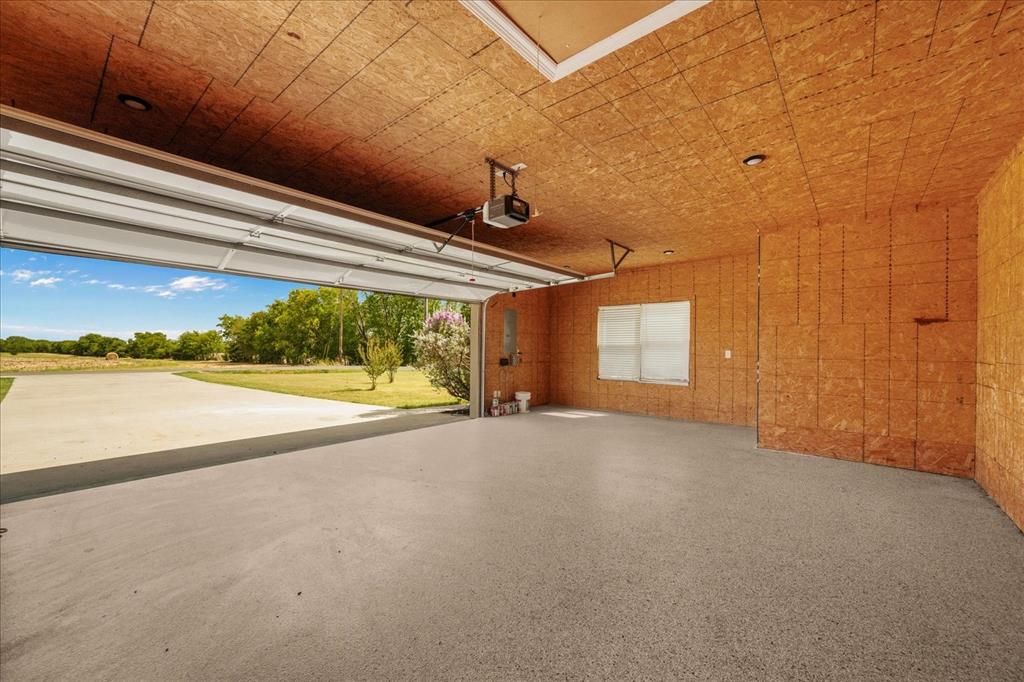 Spacious garage featuring a durable concrete floor, overhead door, and a single window