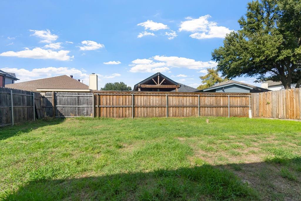 Backyard featuring an expansive lawn, full-perimeter wood fencing, and mature trees