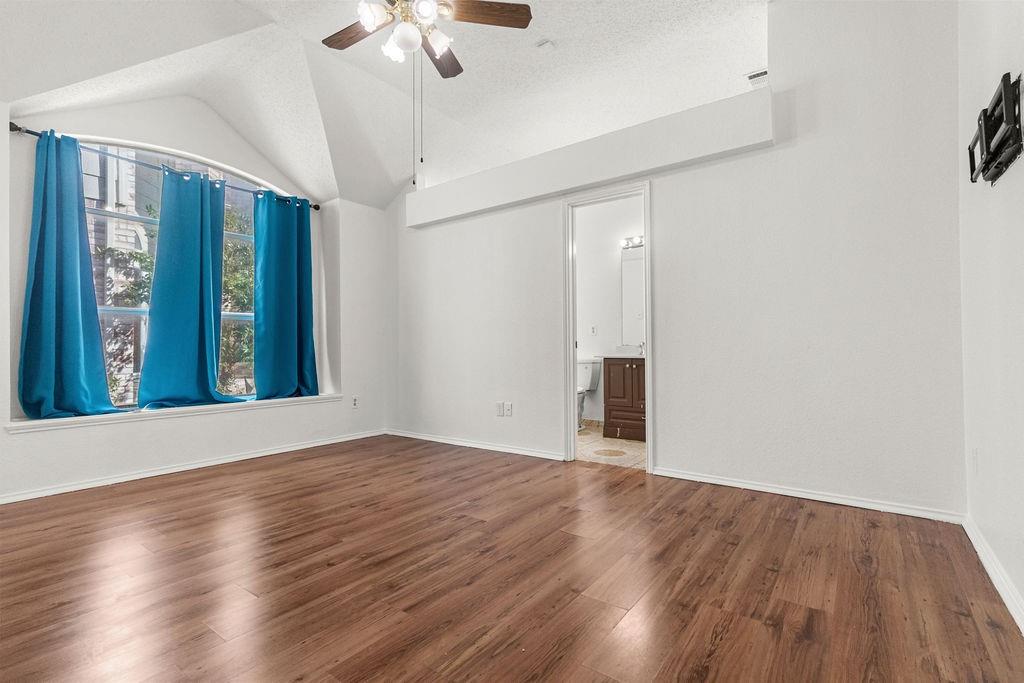 Vaulted ceiling, wood-finish flooring, arched window, and overhead ceiling fan
