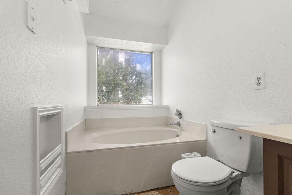 Oval soaking tub featuring an integrated surround, recessed wall niche, and large window