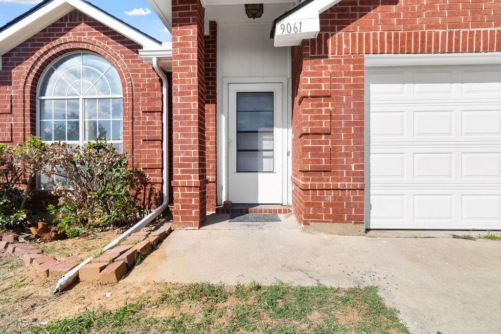 Red brick exterior featuring a multi-panel glass front door, an arched window, and an integrated garage with a white paneled door