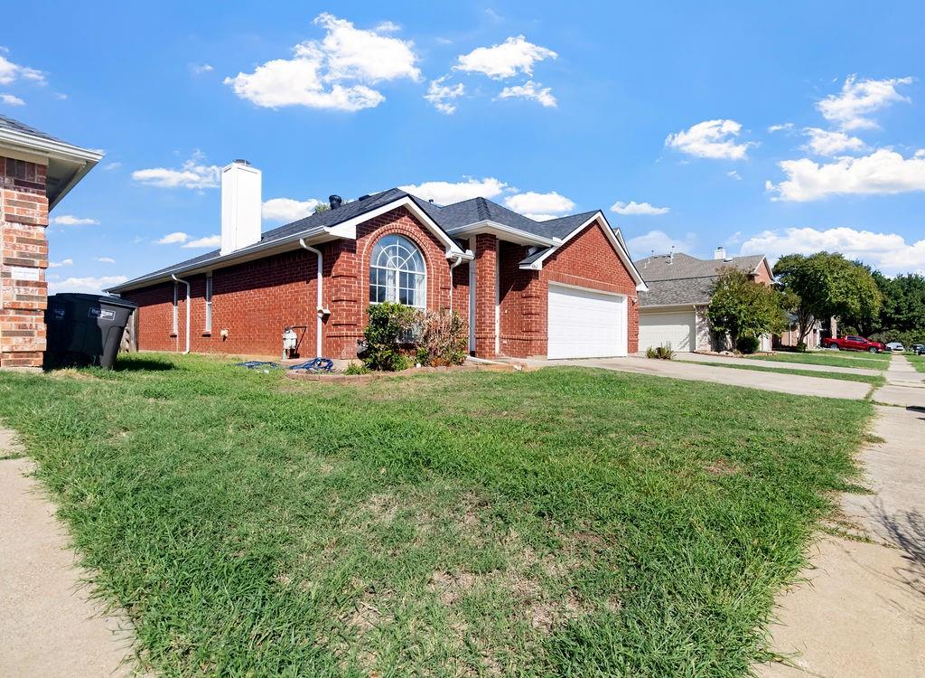 Red brick exterior featuring a prominent arched window, a two-car garage, and a gable roofline