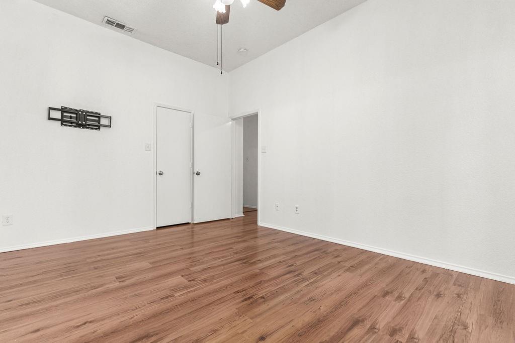 High-ceiling interior featuring wood-finish flooring, a central ceiling fan, and neutral wall tones
