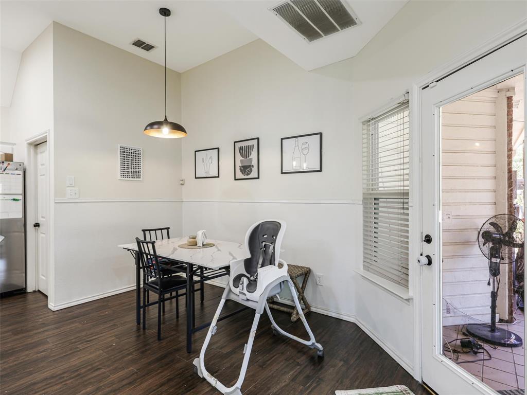 Vaulted ceiling with pendant lighting, wood-finish flooring, and white wainscoting