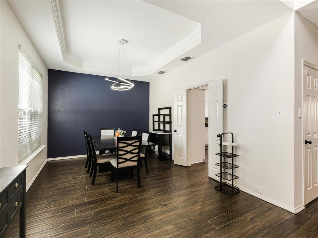 Tray ceiling with crown molding, contemporary chandelier, wood-finish flooring, and white interior doors Tray ceiling with crown molding, contemporary chandelier, wood-finish flooring, and white interior doors