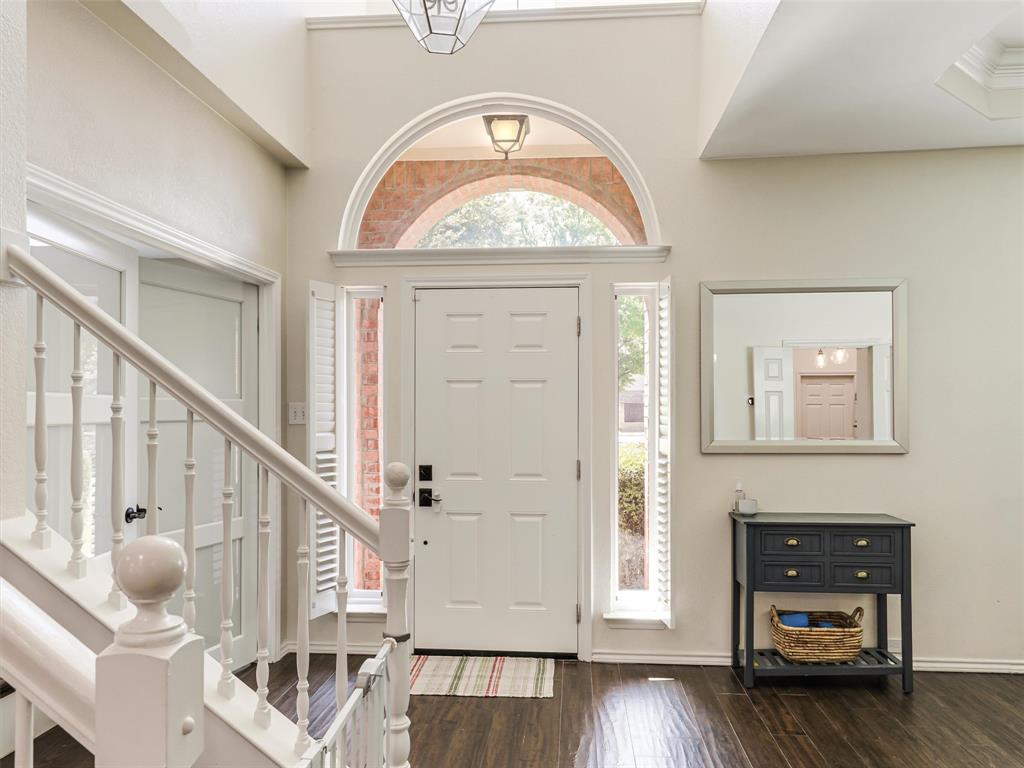 Two-story foyer with high ceilings, dark wood-finish flooring, and white painted balusters Two-story foyer with high ceilings, dark wood-finish flooring, and white painted balusters