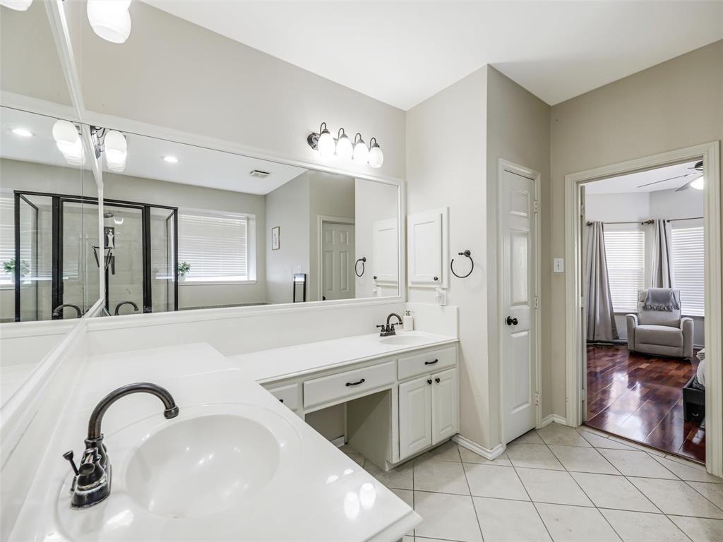 Dual vanity with integral sinks, white cabinetry, dark bronze fixtures, and an expansive mirror