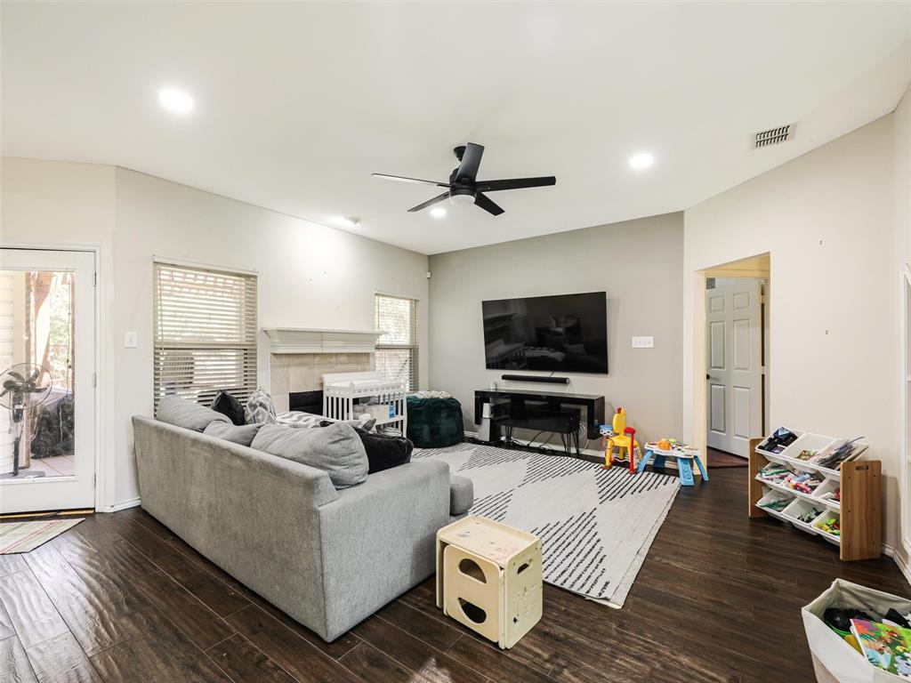 Vaulted ceiling with recessed lighting, wood-finish flooring, and a fireplace with a stone surround
