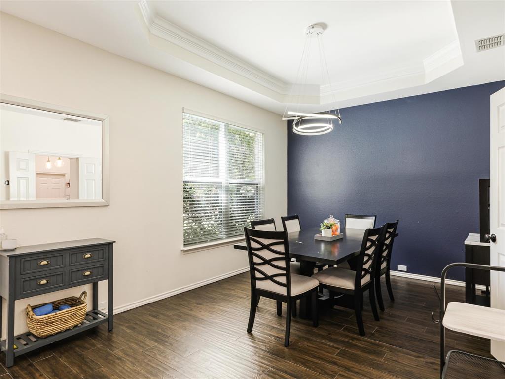 Wood-finish flooring throughout, tray ceiling with crown molding, contemporary chandelier, and a window with blinds Wood-finish flooring throughout, tray ceiling with crown molding, contemporary chandelier, and a window with blinds