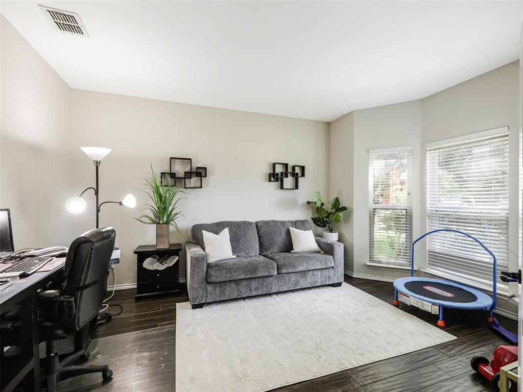 Room featuring wood-finish flooring, two window openings, and neutral wall tones Room featuring wood-finish flooring, two window openings, and neutral wall tones