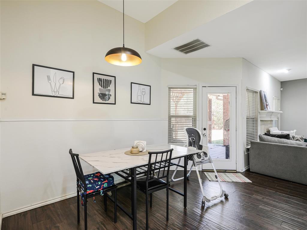 Dining area with wood-finish flooring, a contemporary pendant light fixture, and a glass-paneled door