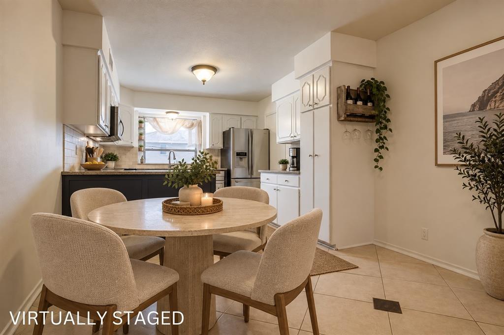 Kitchen with white cabinetry, dark lower cabinets, light-colored tile flooring, and integrated stainless steel appliances