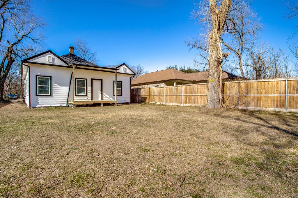 Rear view of house with fence, a yard, and a chimney