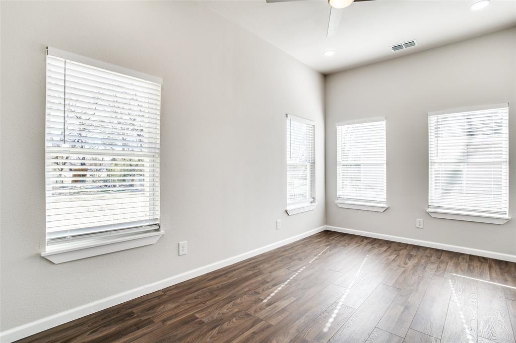 Empty room featuring baseboards, ceiling fan, visible vents, and dark wood-type flooring