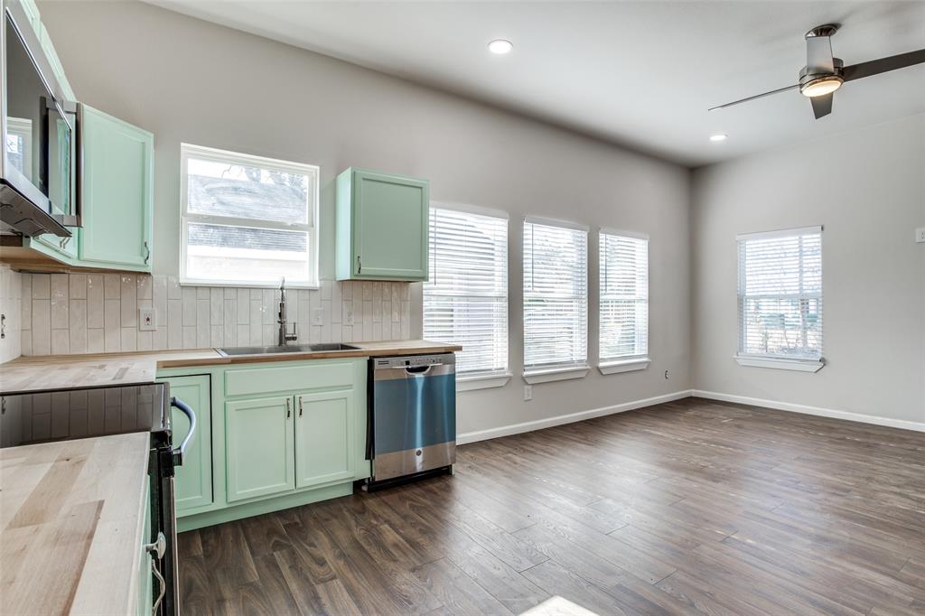 Kitchen featuring wooden counters, stainless steel appliances, tasteful backsplash, a sink, and green cabinetry