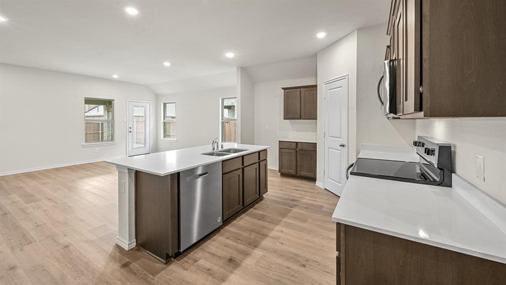 Kitchen featuring wood-finish flooring, recessed lighting, white countertops, stainless steel appliances, and dark wood cabinetry
