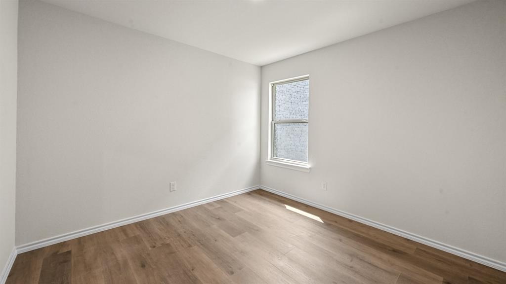 Wood-finish flooring with white trim and a single window