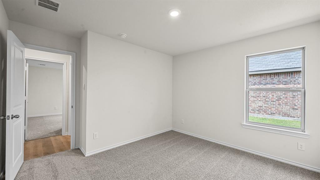 Recessed ceiling lighting, light-colored walls, carpeted flooring, wood-finish flooring in doorway, window with exterior brick detail