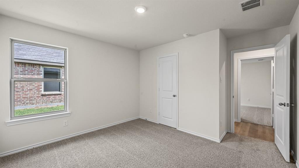 Neutral wall paint, recessed ceiling lighting, textured carpeting, white trim, and a window with exterior brick detail