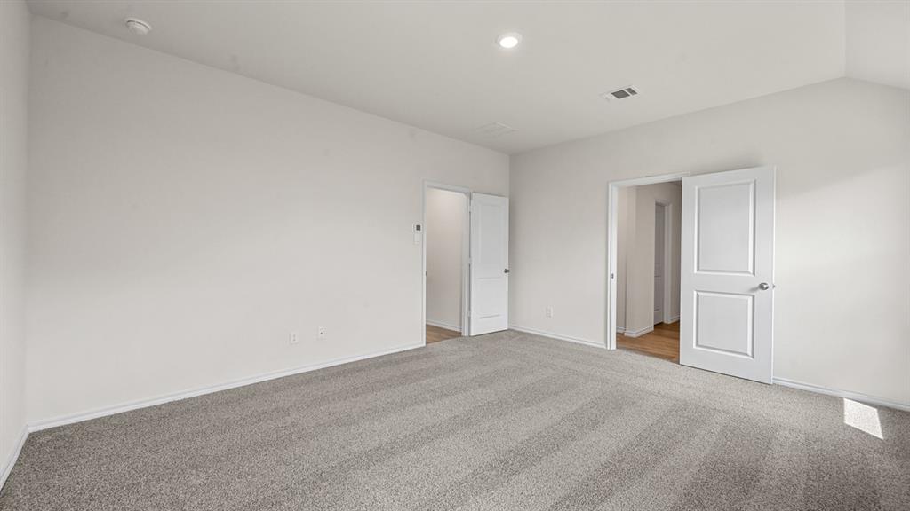 Spacious room featuring vaulted ceilings, light gray carpeting, recessed lighting, and white paneled doors