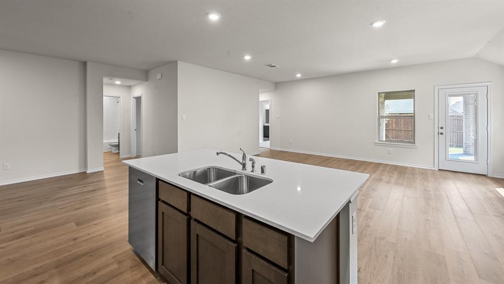 Kitchen island with dual stainless steel sink, white countertop, and dark wood-finish cabinetry