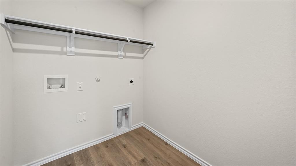 Laundry area featuring wood-finish flooring, white walls, and a built-in hanging rod